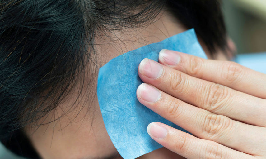 man blotting forehead to remove oil