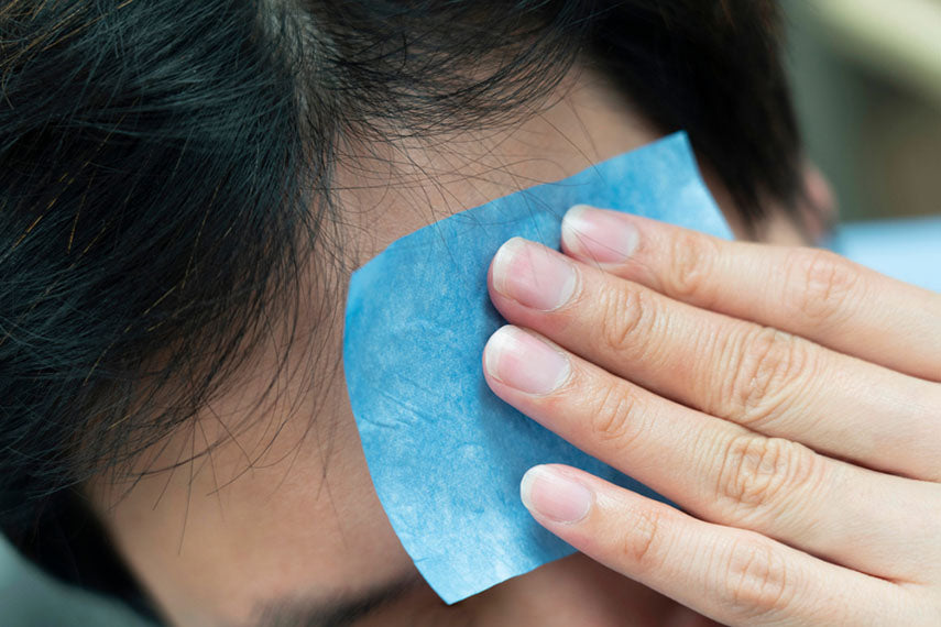 man blotting forehead to remove oil