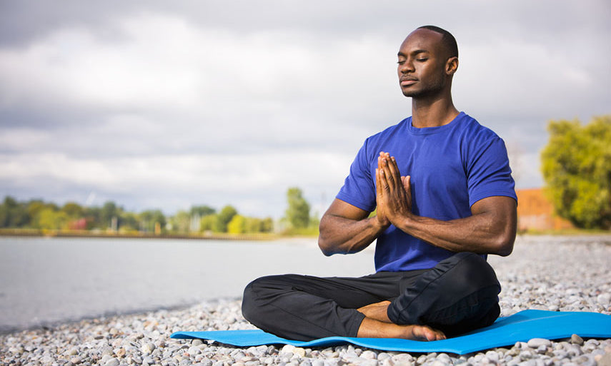 man doing yoga on the beach