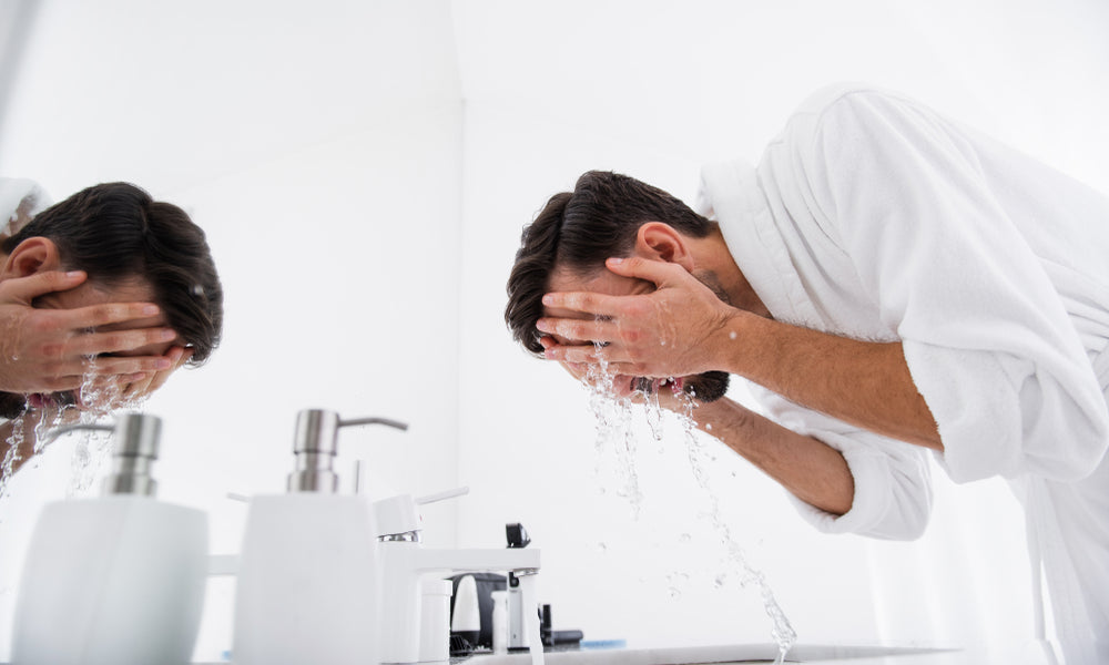 man in robe washing face