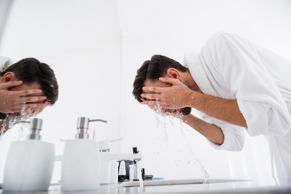 man in robe washing face