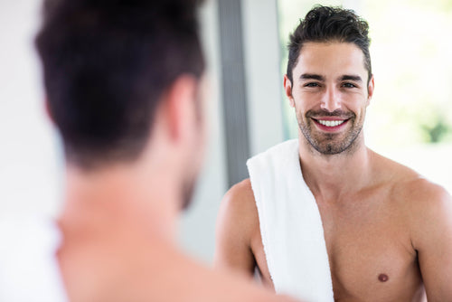 man looking through bathroom mirror