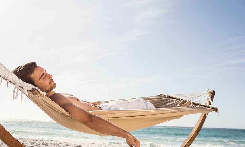 man lounging on beach in hammock