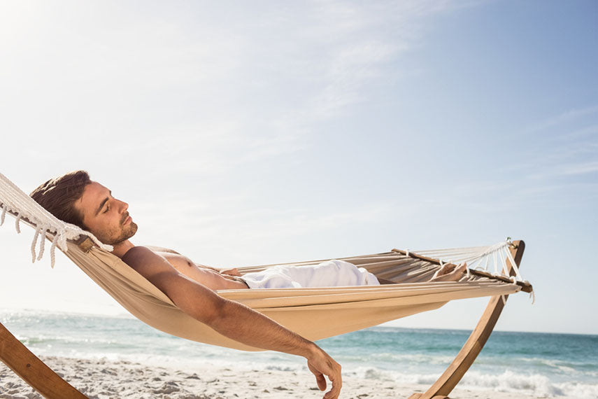 man lounging on beach in hammock