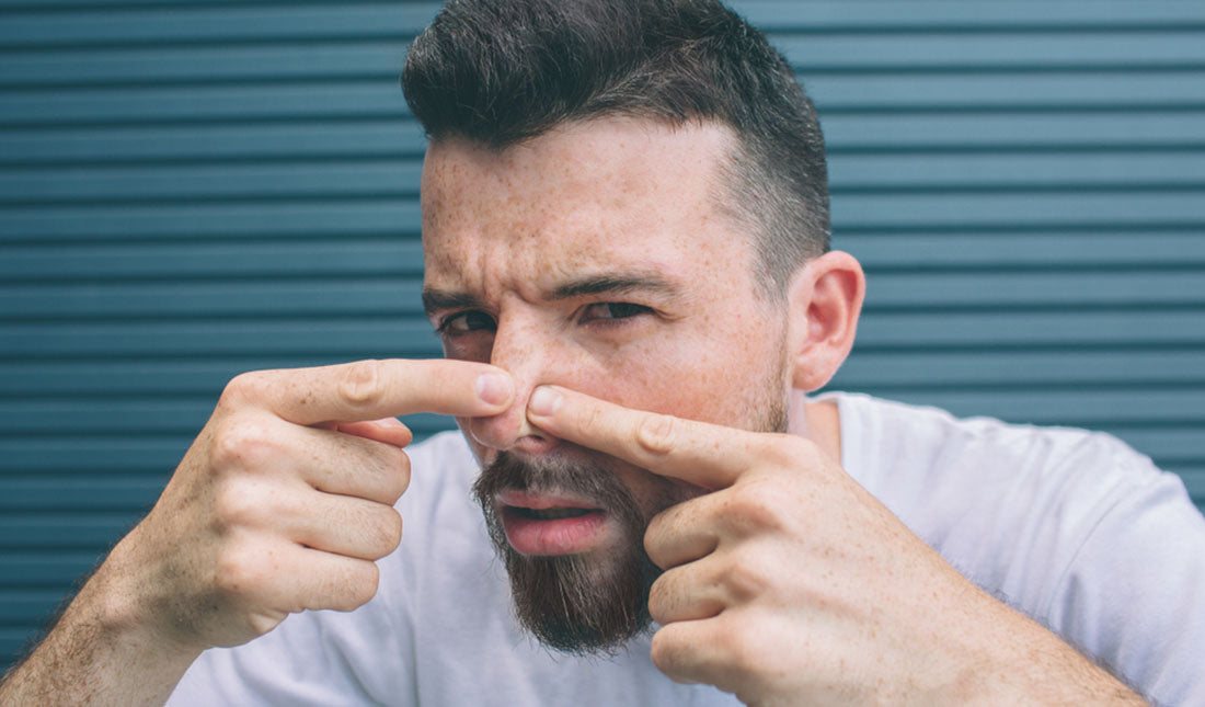 man squeezing tip of nose