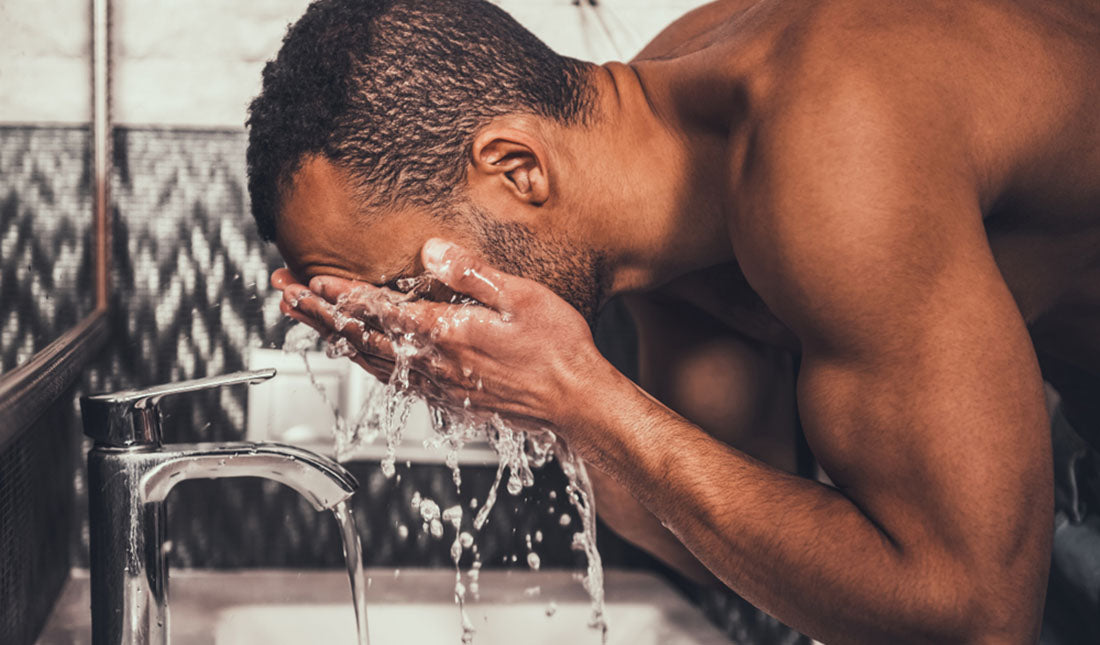 man washing face over sink